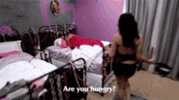 a woman in a bathing suit is walking in a bedroom and asking are you hungry