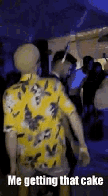 a man in a yellow shirt is standing in front of a crowd of people .