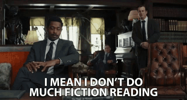 a man in a suit and tie is sitting in a chair with the words i mean i don 't do much fiction reading below him