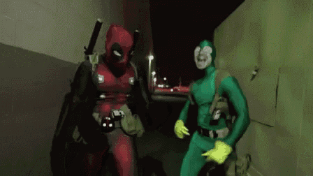 a man in a deadpool costume and a man in a green superhero costume are standing next to each other .