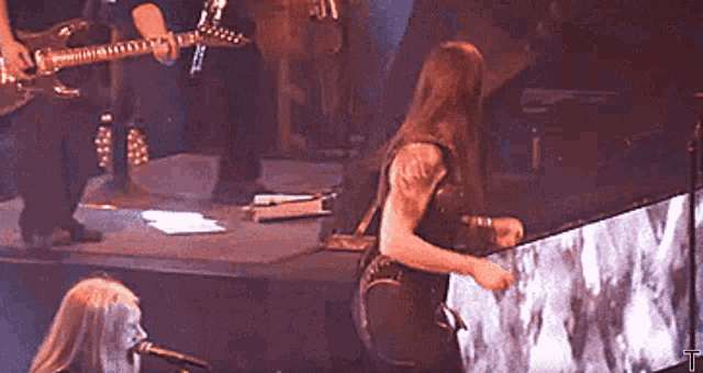 a man playing a guitar and a woman playing a keyboard are on stage