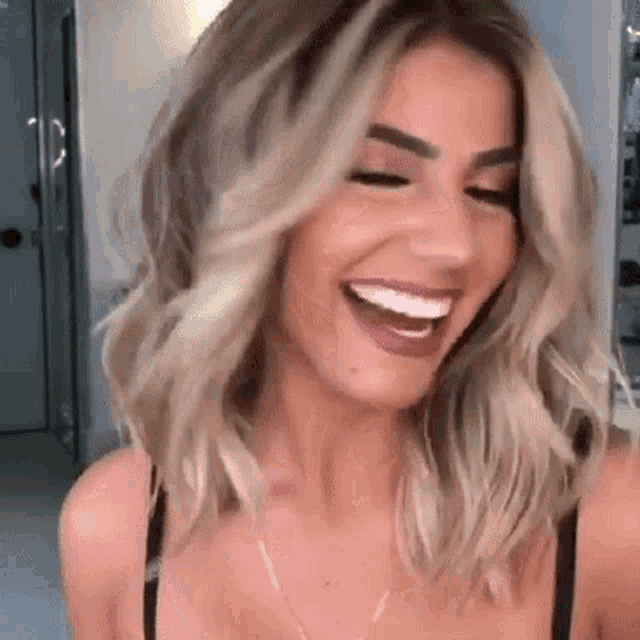 a woman with blonde hair is smiling and wearing a black top .