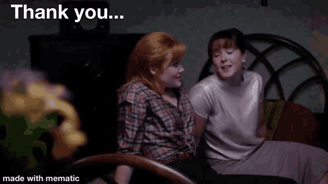 two women are sitting next to each other on a bed and one of them is saying thank you .