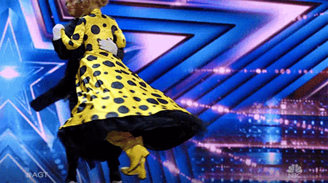 a woman in a yellow dress is dancing with a man