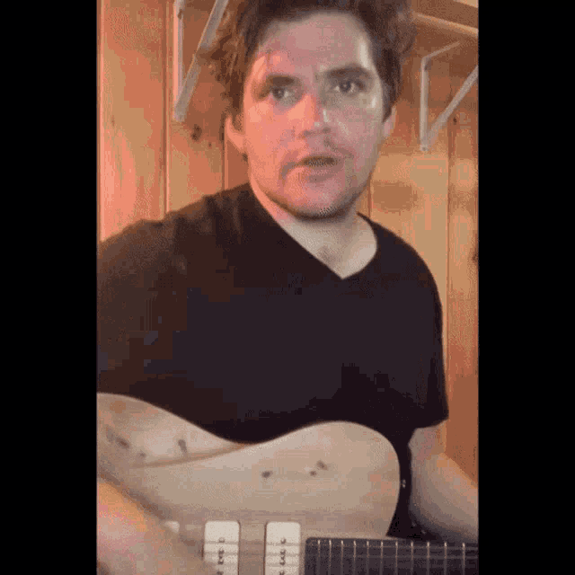 a man in a black shirt playing a guitar
