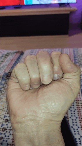 a close up of a person 's fist in front of a television