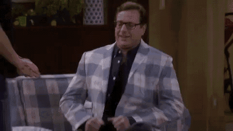 a man in a plaid suit is sitting on a couch .