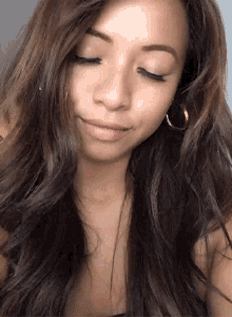 a woman with long hair and hoop earrings is smiling