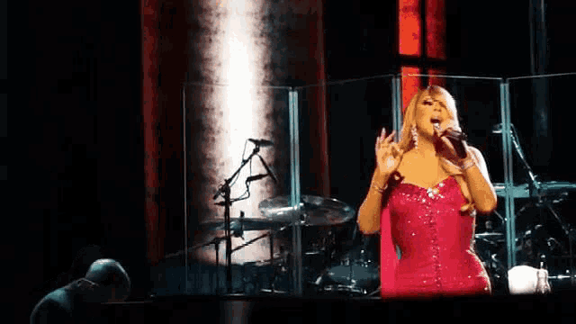 a woman in a red dress singing into a microphone on stage
