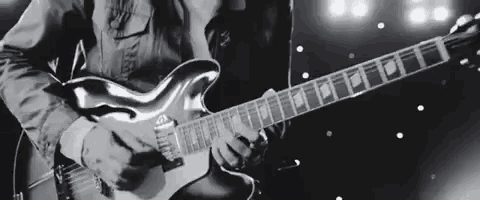 a man is playing an electric guitar on a stage in a black and white photo