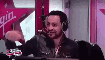 a man wearing headphones is sitting in front of a microphone in a studio .