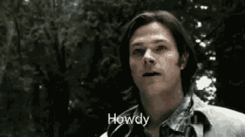 a man is standing in a forest with trees in the background and talking to someone .