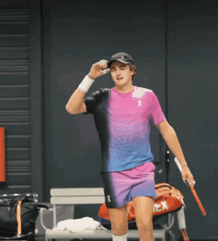 a man holding a tennis racquet and wearing a shirt that says on on it