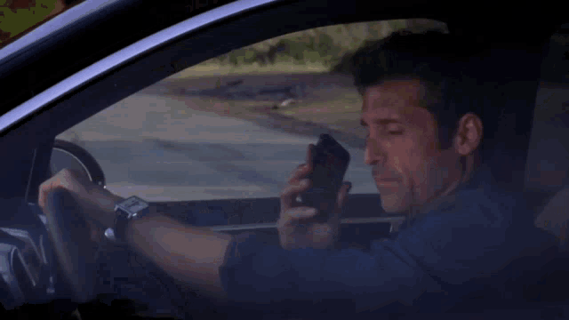 a man is talking on a cell phone in a car