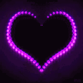a purple heart is surrounded by purple lights on a dark background