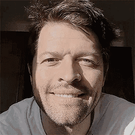 a man with a beard is smiling for the camera while wearing a white shirt .