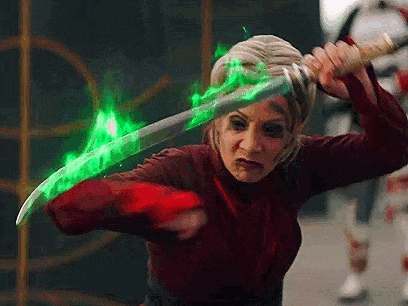 a woman is holding a sword with a green glowing blade .