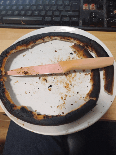 a burnt pizza on a white plate with a knife