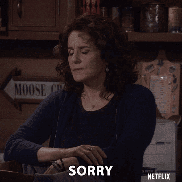 a woman with a moose sign behind her says sorry