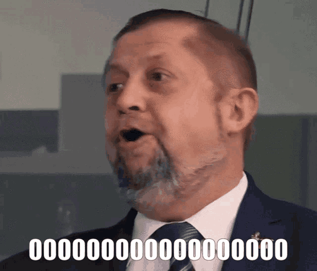 a man in a suit and tie has a surprised look on his face and the word 000000 is on the bottom right