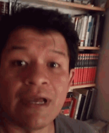 a man is taking a selfie in front of a bookshelf