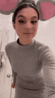 a woman wearing a mouse headband and a cat face mask takes a selfie