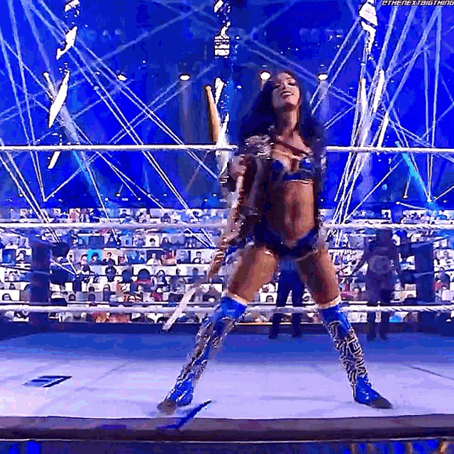a woman is standing on a wrestling ring in front of a crowd while dancing .