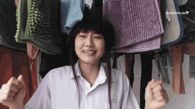 a girl in a white shirt stands in front of a bunch of towels hanging from the ceiling