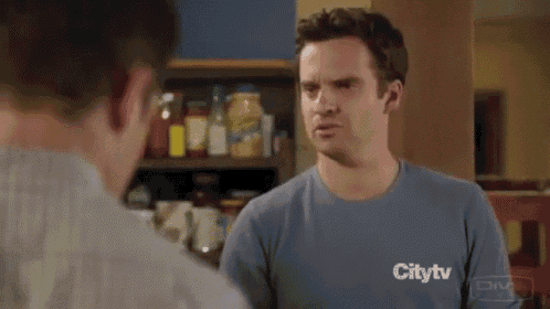 a man in a plaid shirt is standing next to another man in a kitchen .