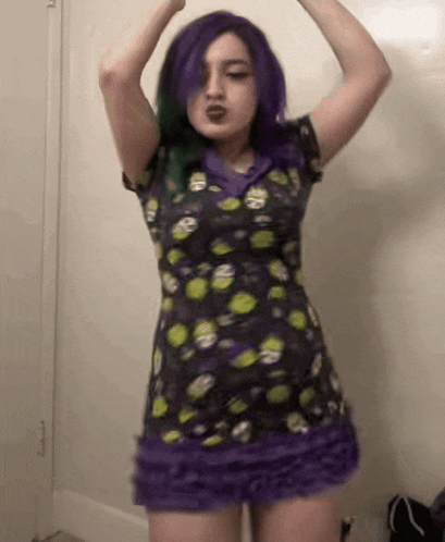 a woman with purple hair and green eyes is wearing a purple dress