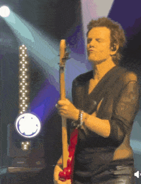 a man in a black shirt playing a guitar on stage