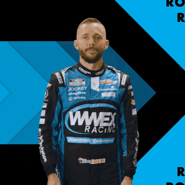 a man in a wwex racing jacket stands in front of a blue background