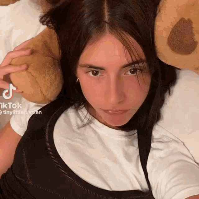 a girl is laying on a bed with a teddy bear and a tiktok watermark