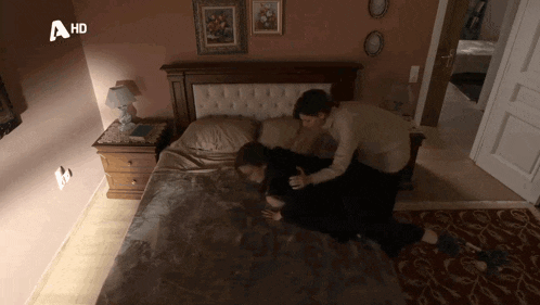 a couple laying on a bed with a hd logo on the bottom right