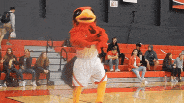 a mascot is dancing on a basketball court in front of a crowd