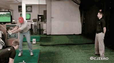 a man is swinging a golf club at another man in a golf simulator