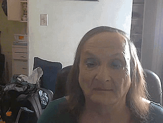 a woman with long hair is sitting in a chair in a room .