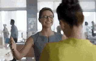 two women are standing next to each other in an office .
