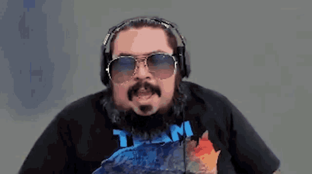 a man with a beard and sunglasses is wearing headphones and a t-shirt that says `` team '' .