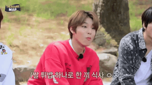 a boy in a red sweater is sitting next to another boy in a treasure map shirt