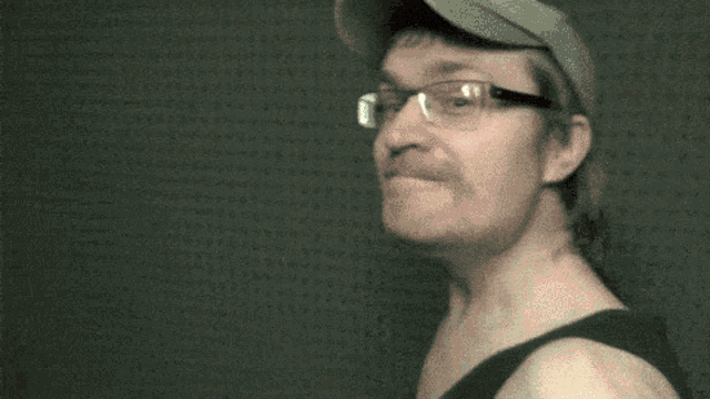 a man wearing glasses and a hat is making a face