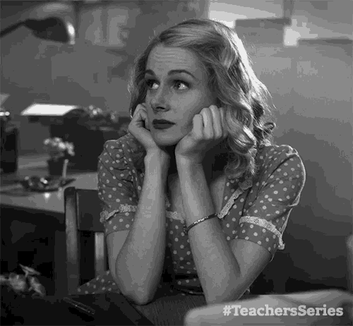 a woman in a polka dot dress is sitting at a desk with her hands on her chin .. #teachersseries