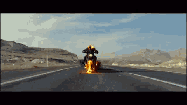 a man is riding a burning motorcycle down a desert road