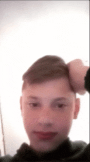a blurry picture of a young boy with his hand on his head