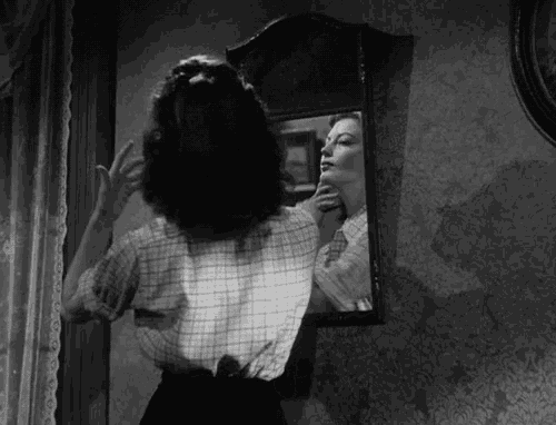 a woman is looking at herself in a mirror