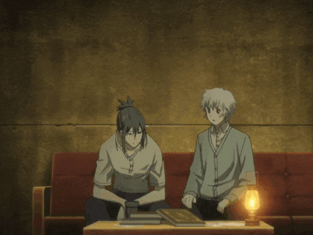 two anime characters are sitting on a couch with a book on the table