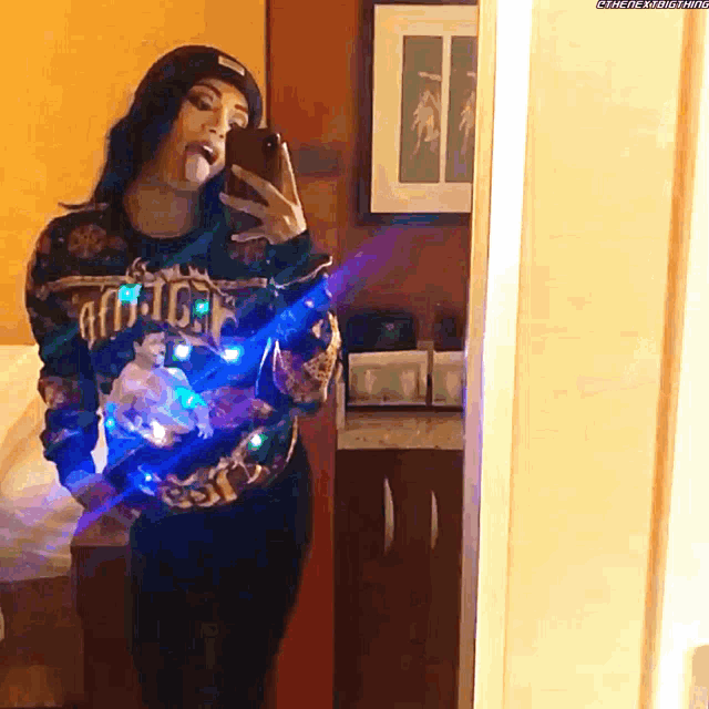 a woman is taking a selfie in front of a mirror with her tongue sticking out
