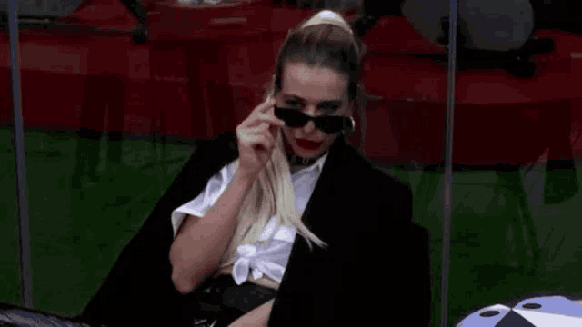 a woman wearing sunglasses and a scarf is sitting in a chair .