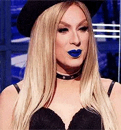 a woman wearing a hat and blue lipstick is standing in front of a mirror .