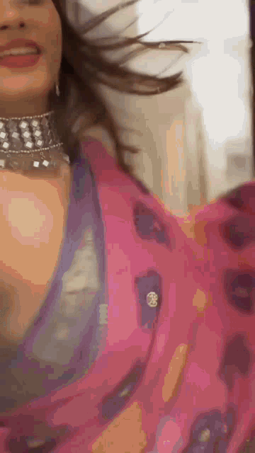 a woman is wearing a pink saree and a choker .